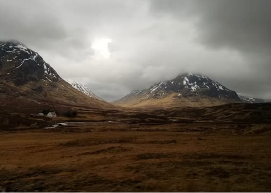 cloudy field with munros in background