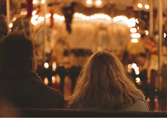 romantic couple sat on bench looking to lit nighttime scene