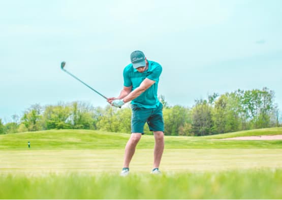 golfer swinging club on st andrews golf course