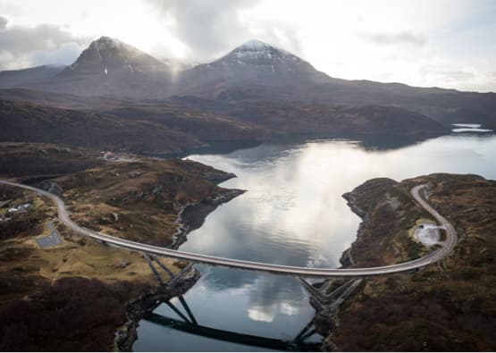 bridge with winding road by loch and river