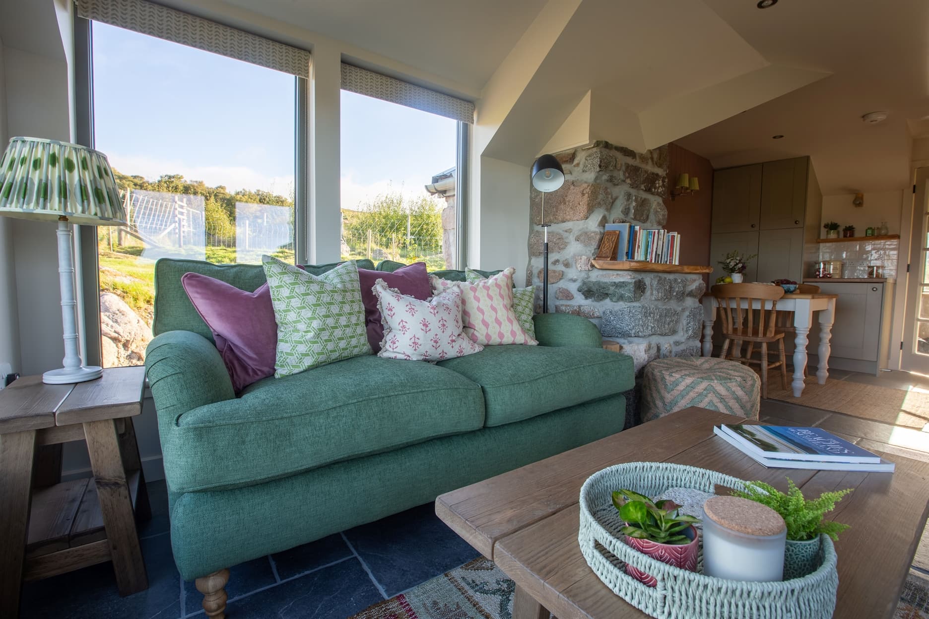 Living room with green sofa, colourful cushions and coffee table in foreground