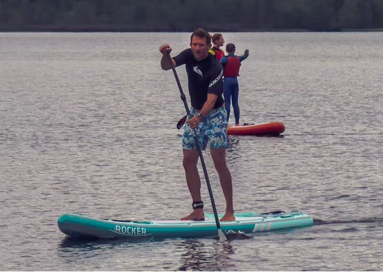 family members paddleboarding on loch