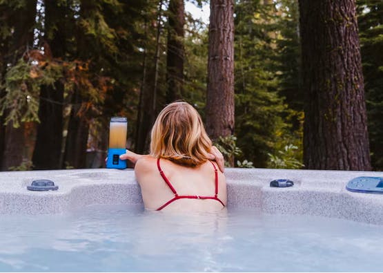 member of couple sitting in hot tub looking out to nature