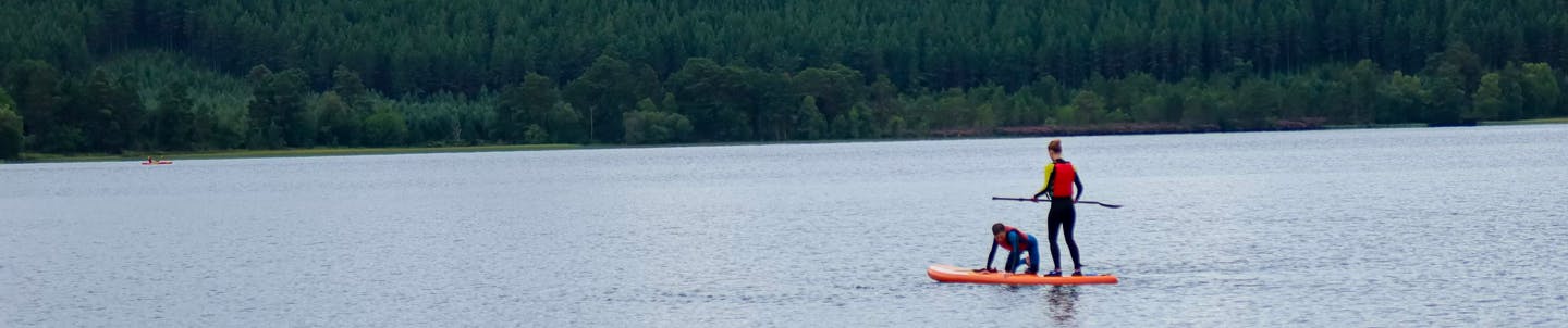 couple paddleboarding in aviemore